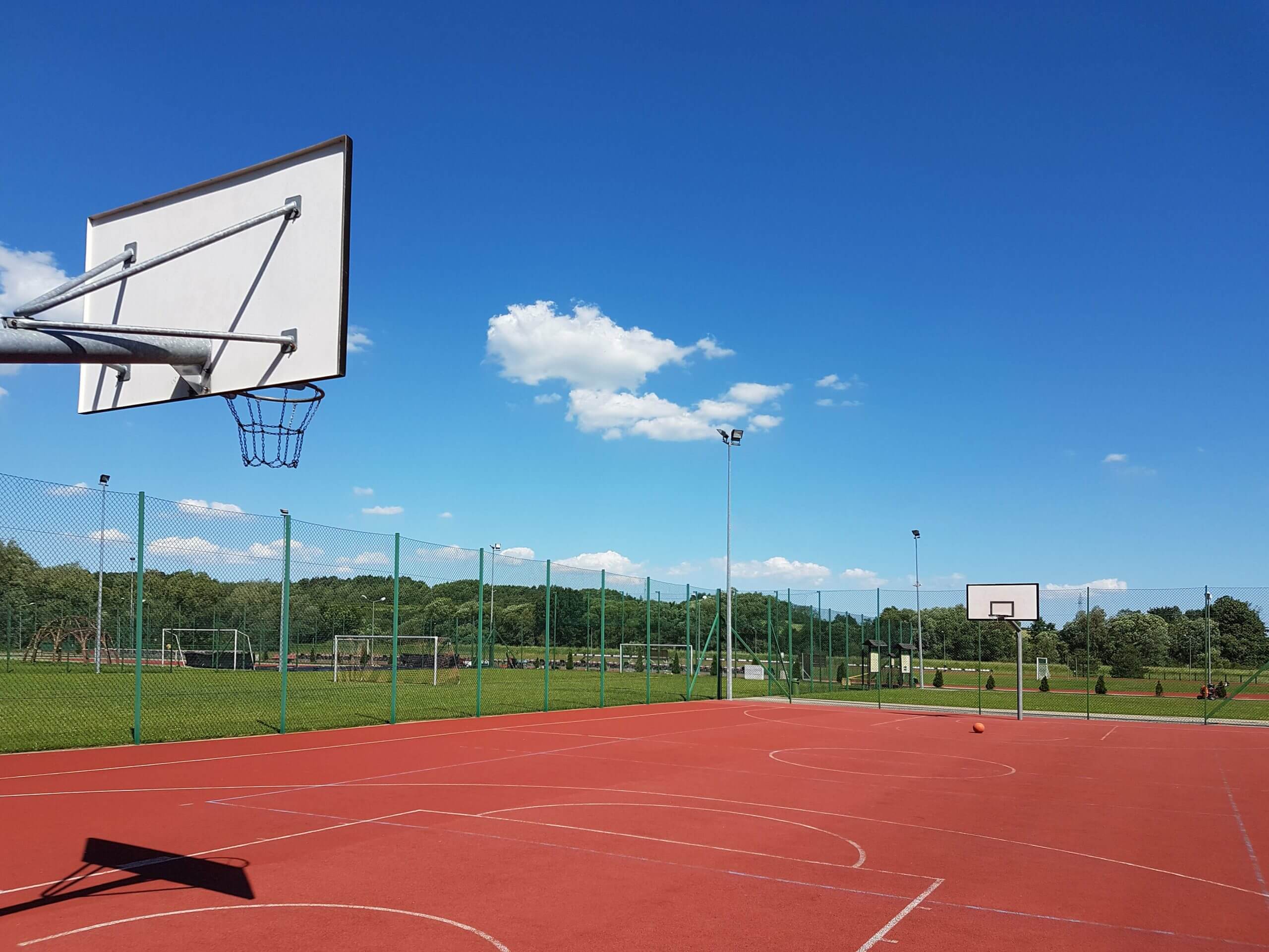 Modern basketball court under the open sky with artificial red coating. Location of team sports events. Physical education of citizens. Healthy lifestyle. Urban infrastructure for recreation, interest
